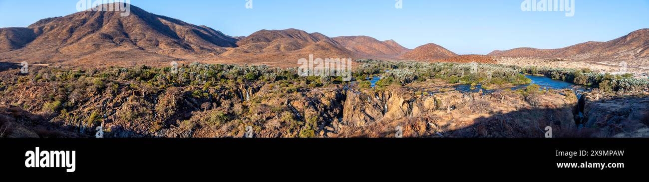 Panorama, fiume Kunene con vegetazione verde nel paesaggio secco delle montagne rosse, cascata e baobab africano (Adansonia digitata), alla luce della sera Foto Stock