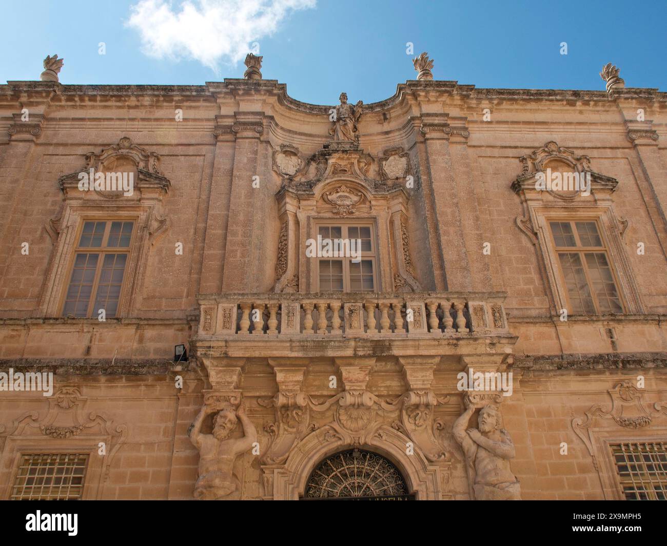 Edificio barocco con facciate ornate, finestre e statue sotto un cielo leggermente nuvoloso, la città di mdina sull'isola di malta con case storiche Foto Stock
