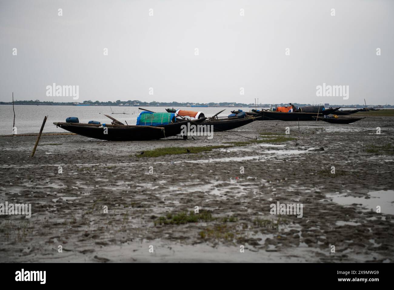 Le barche da pesca sono viste sulla riva del fiume Pasur durante le conseguenze a Mongla. Il ciclone Remal, che ha avuto origine nel Golfo del Bengala, ha colpito i distretti costieri meridionali del Bangladesh nella notte di domenica 26 maggio. Il ciclone ha portato con sé velocità devastanti del vento da 90 a 120 km/h, con conseguenti estese inondazioni e distruzione. I Sundarbans, una barriera naturale critica e sito patrimonio dell'umanità dell'UNESCO, hanno subito il peso dell'impatto del ciclone. Le acque alluvionali si sono innalzate da tre a quattro metri sopra la norma, sommergendo vaste aree e causando danni significativi alla fauna selvatica e alle infrastrutture, in Foto Stock