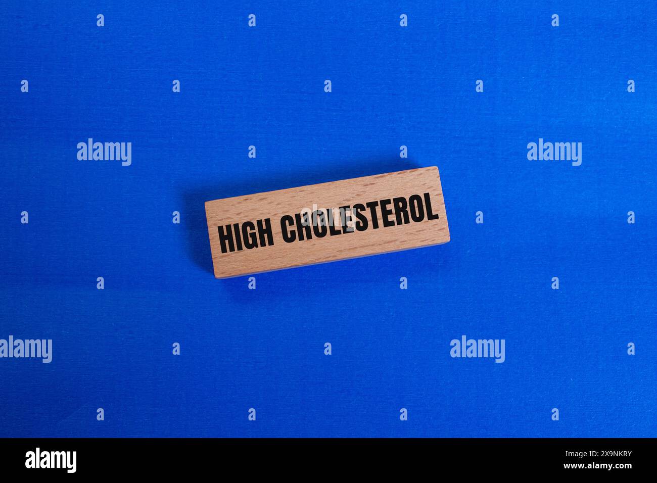 Messaggio di colesterolo alto scritto su un blocco di legno con sfondo blu. Simbolo concettuale di colesterolo alto. Copia spazio. Foto Stock