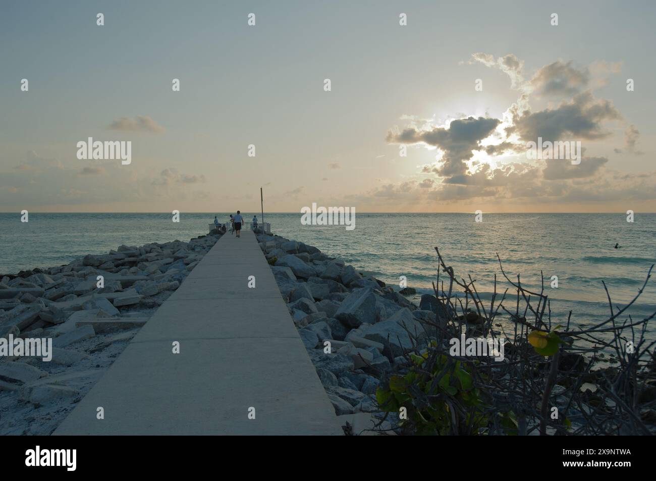 Ammira il tramonto a ovest alla spiaggia Fishing Pier Pass-a-Grille a St Petersburg, Florida. Le linee principali marciscono verso l'acqua. Bagliore d'oro e cielo blu del sole Foto Stock