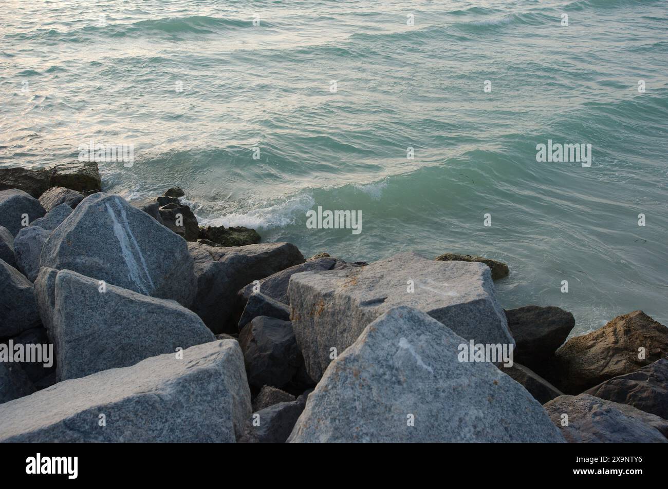 Vista media delle grandi rocce sul bordo della costa vicino al tramonto in Florida. Più colori e onde che si infrangono a circa 45 gradi. Tendina parasole Foto Stock