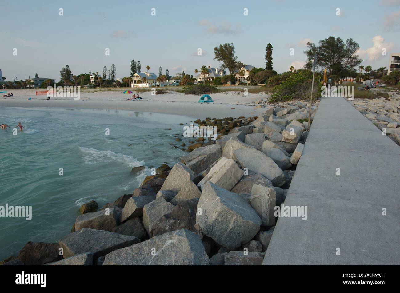 Ammira il tramonto a est dalla spiaggia Fishing Pier Pass-a-Grille di St Petersburg, Florida. Le linee principali marciapiede portano alla spiaggia. Bagliore dorato e cielo blu Foto Stock