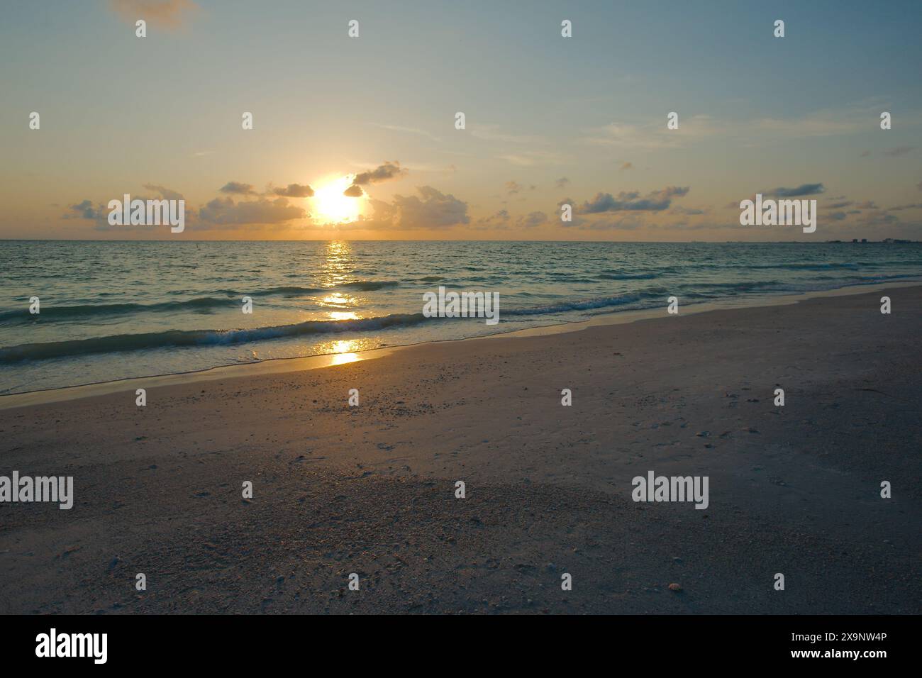 Ampia vista della spiaggia Pass-a-Grille di St. Pete Beach, Florida, guardando a nord-ovest. Ampia sabbia e onde in acqua, vicino al tramonto con acqua blu Foto Stock