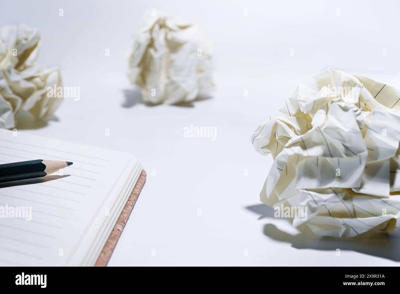 Blocco appunti vuoto con matita e palle di carta increspate, bozze scartate durante il processo di sviluppo, concetto di frustrazione aziendale, stress e cre Foto Stock