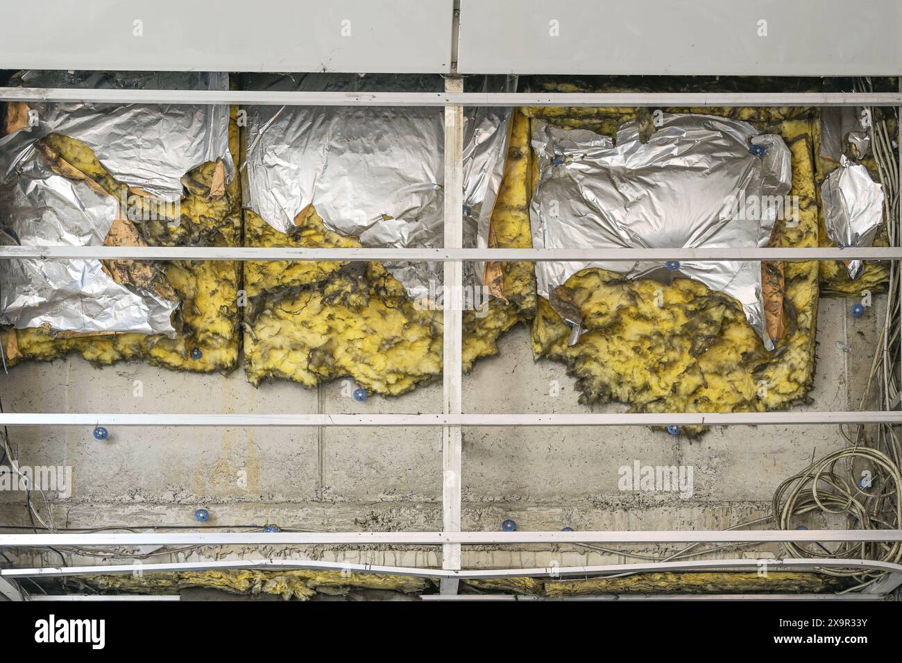 Isolamento demolito con tracce di incendio su un muro di cemento dietro un coperchio aperto della facciata di un edificio, concetto di ingegneria delle costruzioni e il Foto Stock
