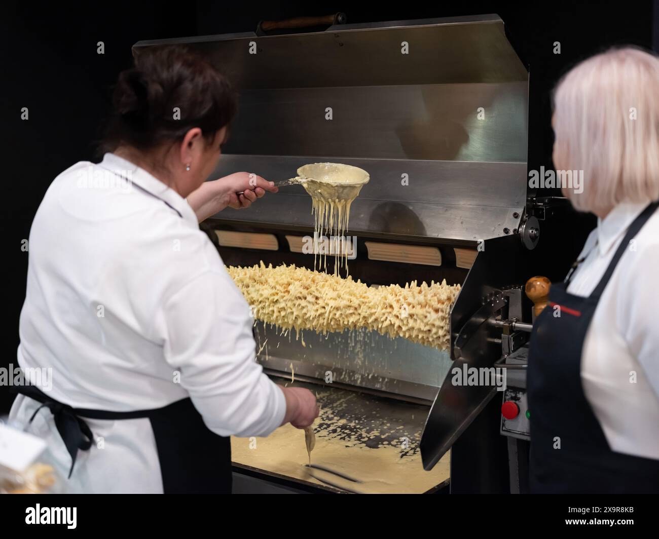 Berlino, Germania 20.01.2023. Due donne irriconoscibili stanno cucinando la torta lituana agli alberi, sakotis o baumkuchenas, sekacz polacco, ba bielorussa Foto Stock