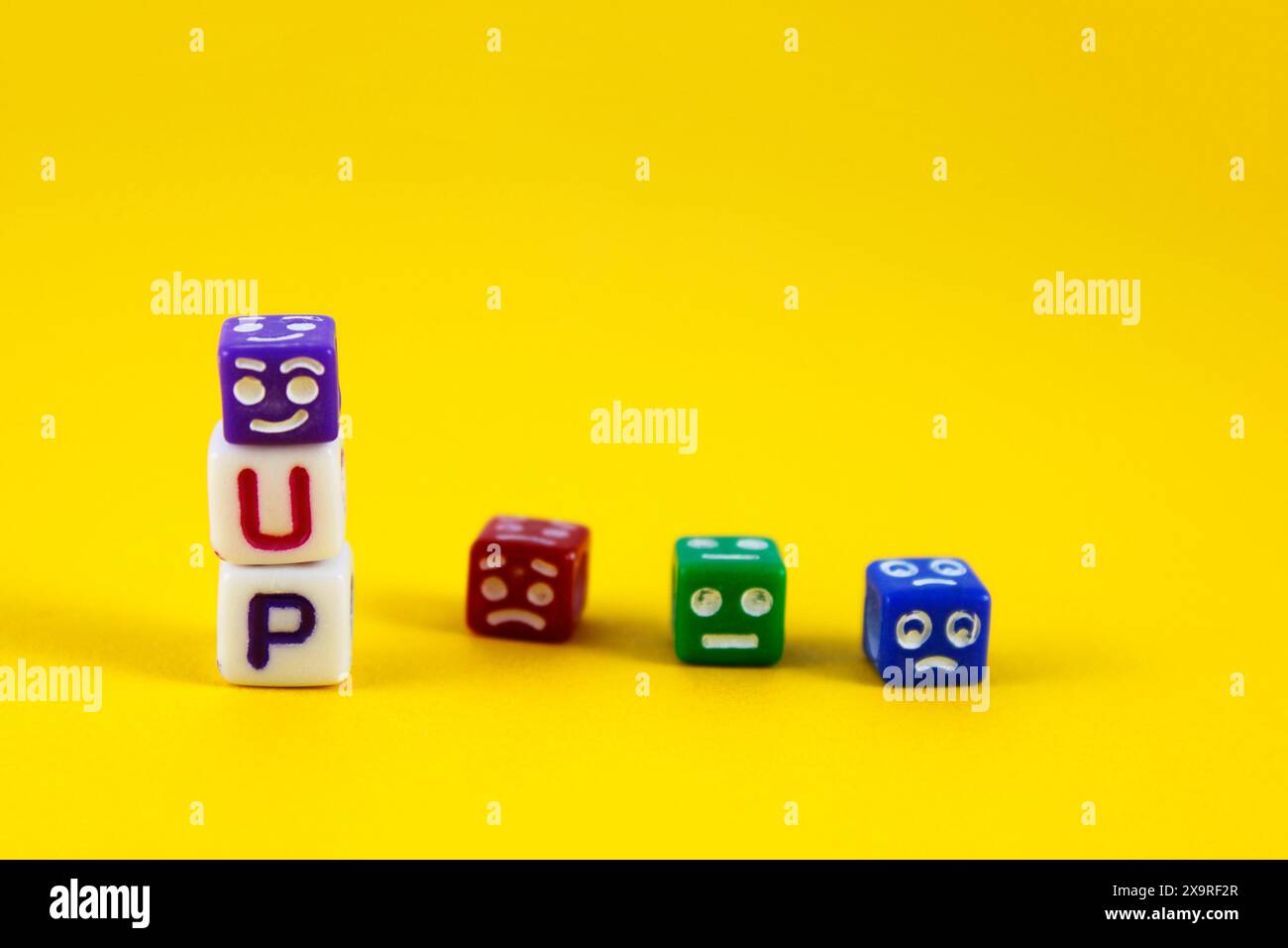 Cubo felice sulla parola accanto ad altri cubi con espressioni tristi Foto Stock
