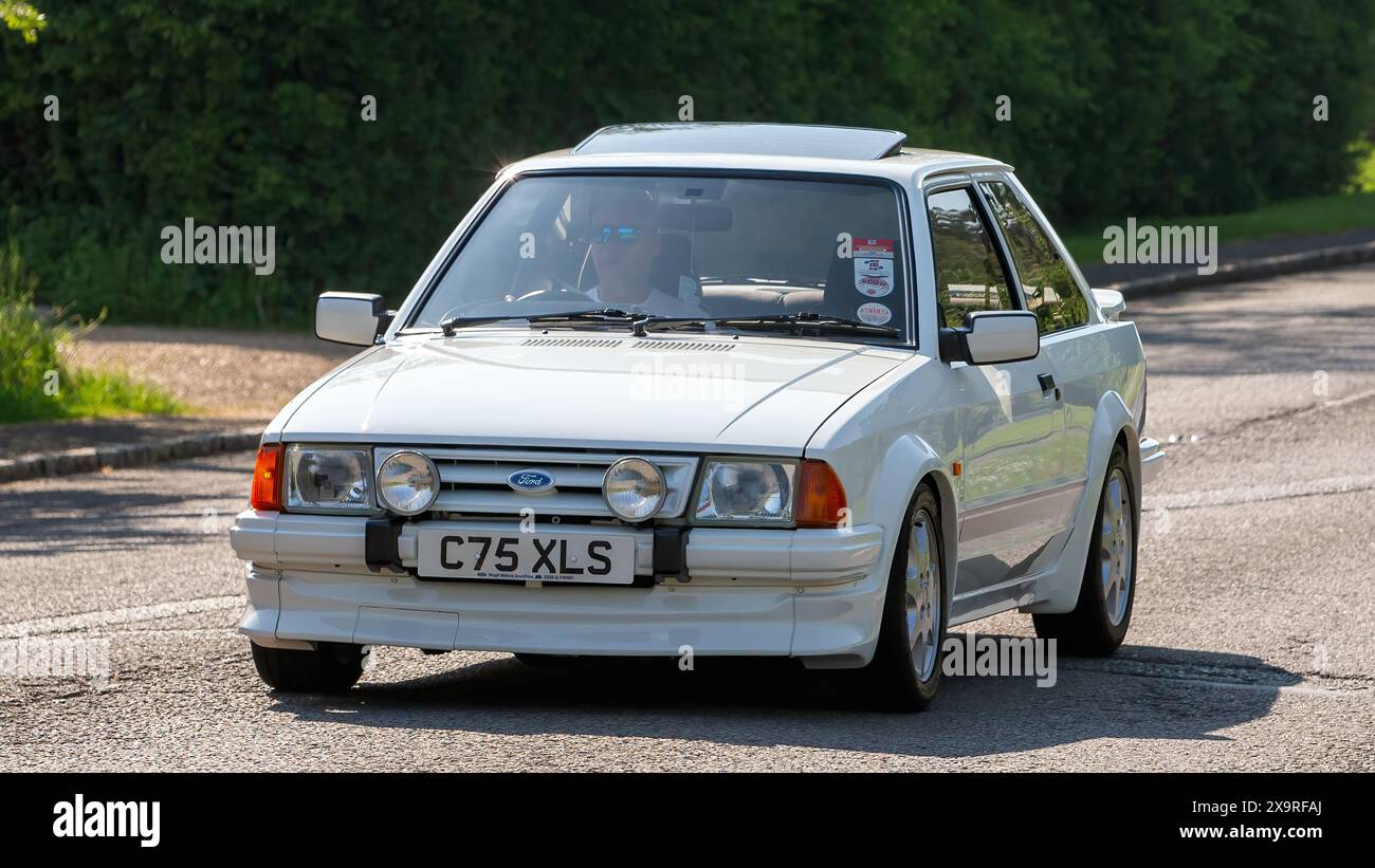 Stoke Goldington, Regno Unito - 11 maggio 2024: 1986 Ford Escort rs turbo car bianca che guida su una strada britannica Foto Stock