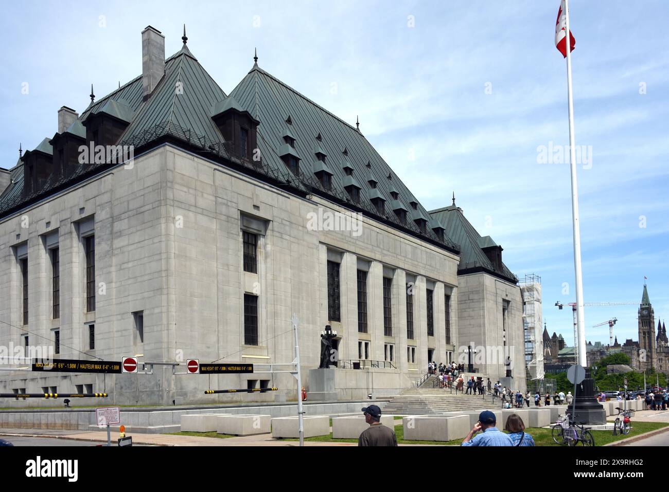 Ottawa, Canada - 1 giugno 2024: Un gruppo di persone si allinea per vedere l'interno dell'edificio della Corte Suprema come parte dell'evento annuale Doors Open che consente alle persone di vedere all'interno e conoscere i vari edifici della zona. La Peace Tower può essere vista sulla destra. Foto Stock