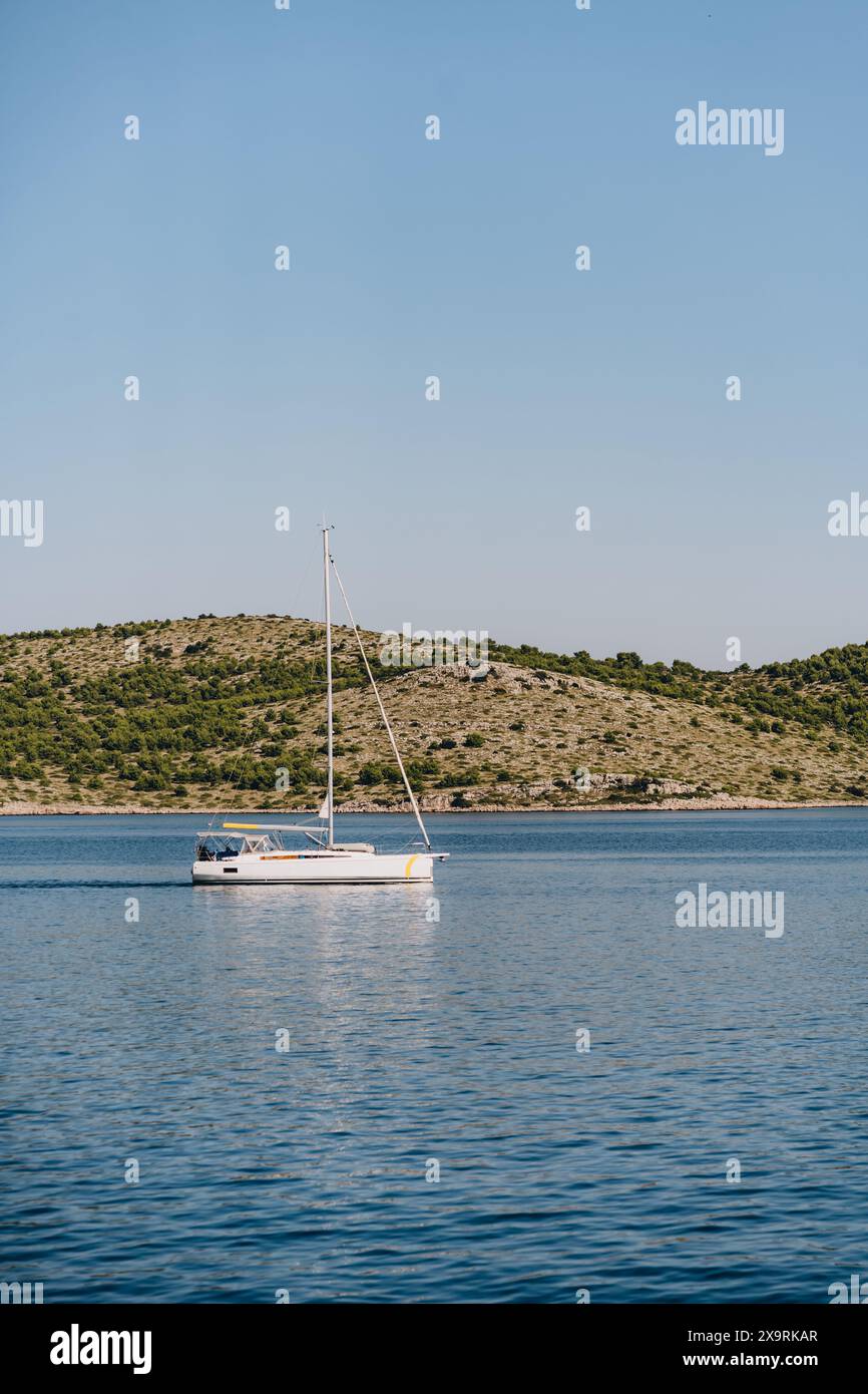 Barca a vela lungo la spiaggia dell'isola di Dugi Otok sotto il cielo blu, fuga nel mare Adriatico, Croazia Foto Stock