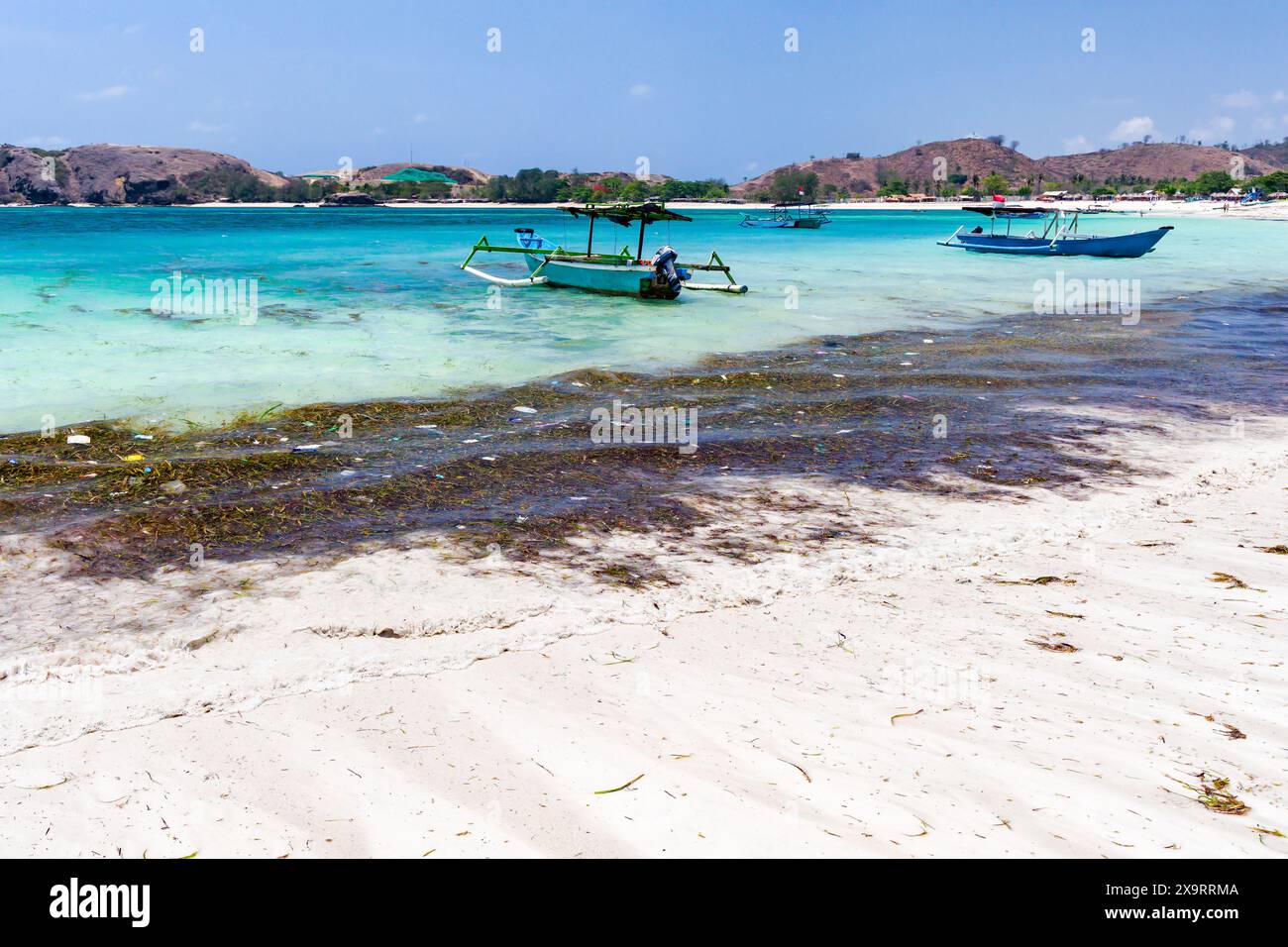 Barca accanto alla plastica galleggiante e alla spazzatura in un caldo oceano tropicale a Tanjung Aan, Lombok, Indonesia Foto Stock