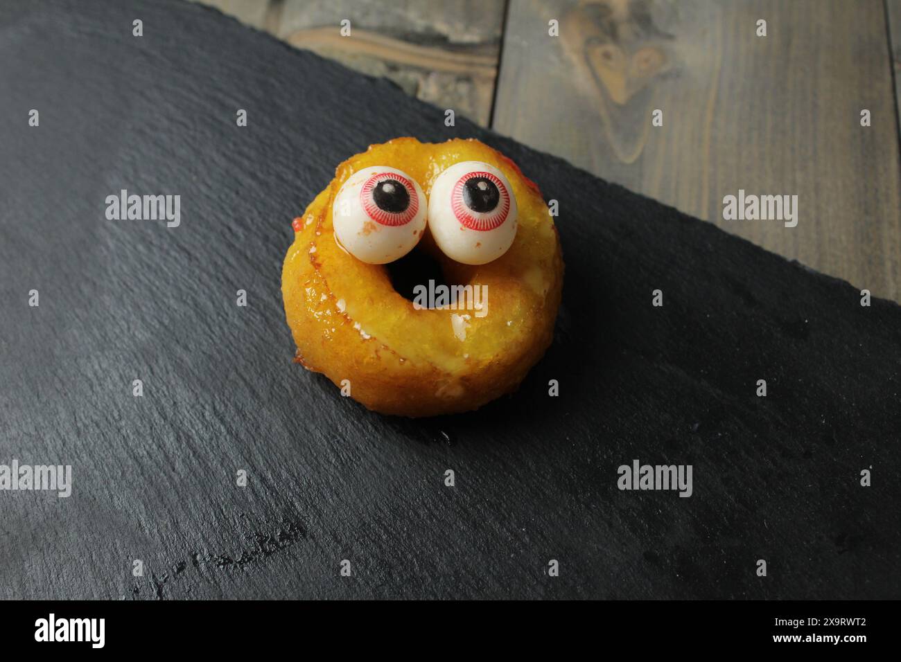 Torta di ciambelle gialla con occhi su sfondo grigio con spazio per testo di copispazio. Concetto di preparazione per la vacanza. Foto Stock