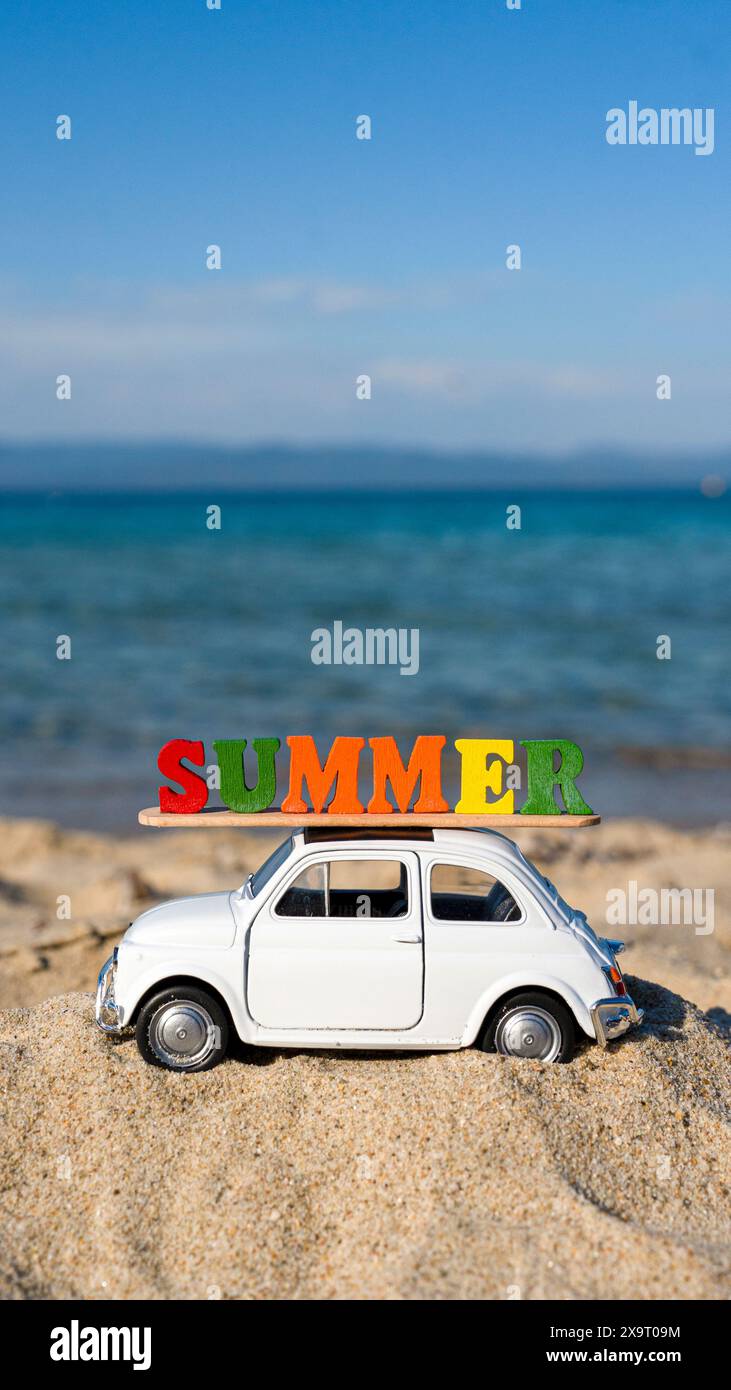 Bella auto con cartello estivo sul tetto sulla spiaggia pronta per le vacanze estive Foto Stock