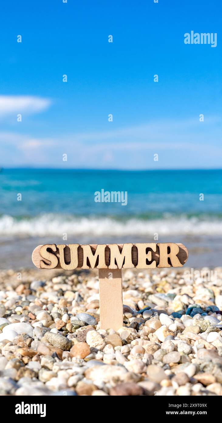 Insegna estiva in legno sulla splendida spiaggia rocciosa Foto Stock