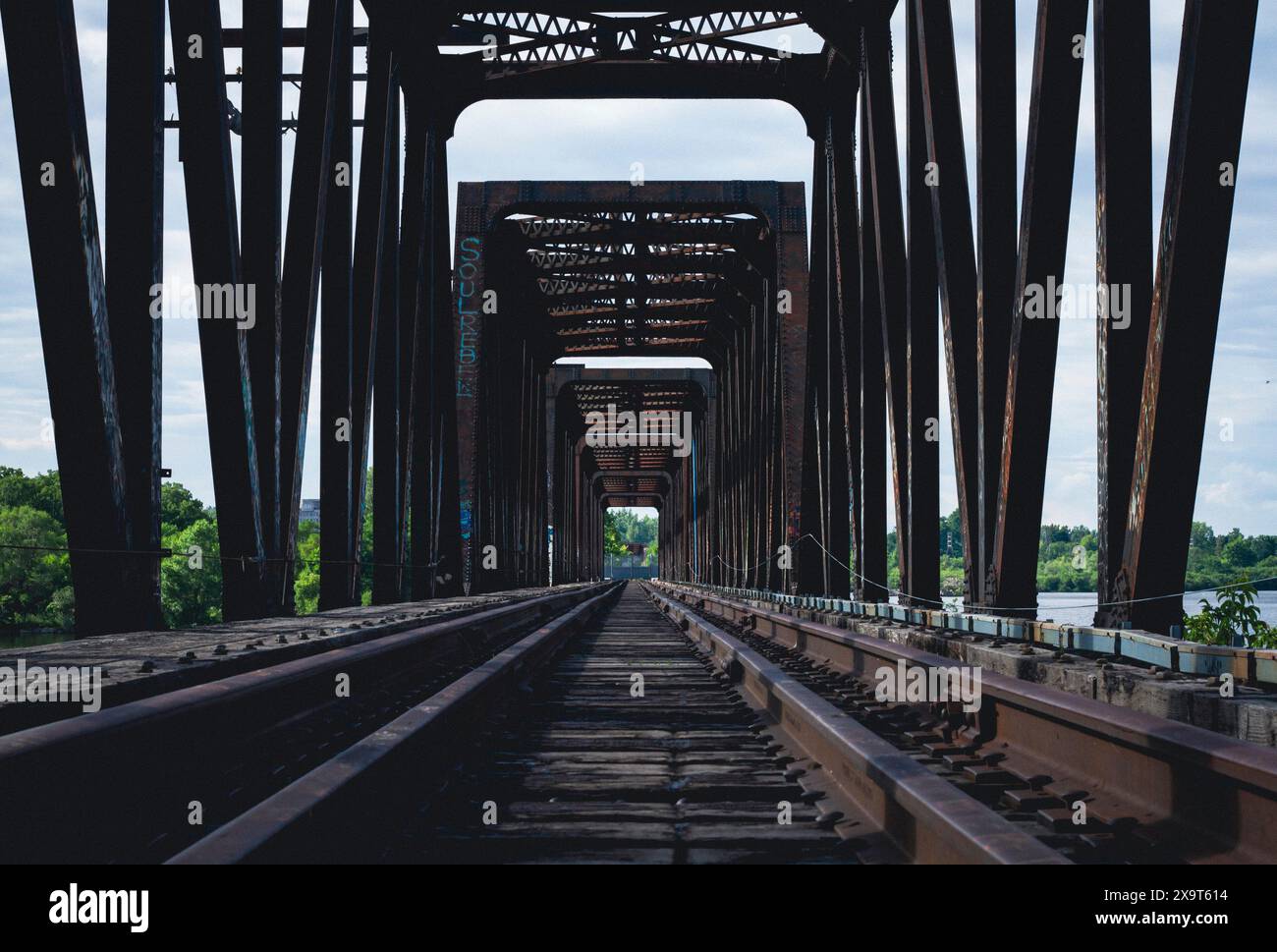 Un ponte ferroviario vuoto e simmetrico che conduce verso una lussureggiante foresta verde ai margini di Ottawa Ontario Foto Stock