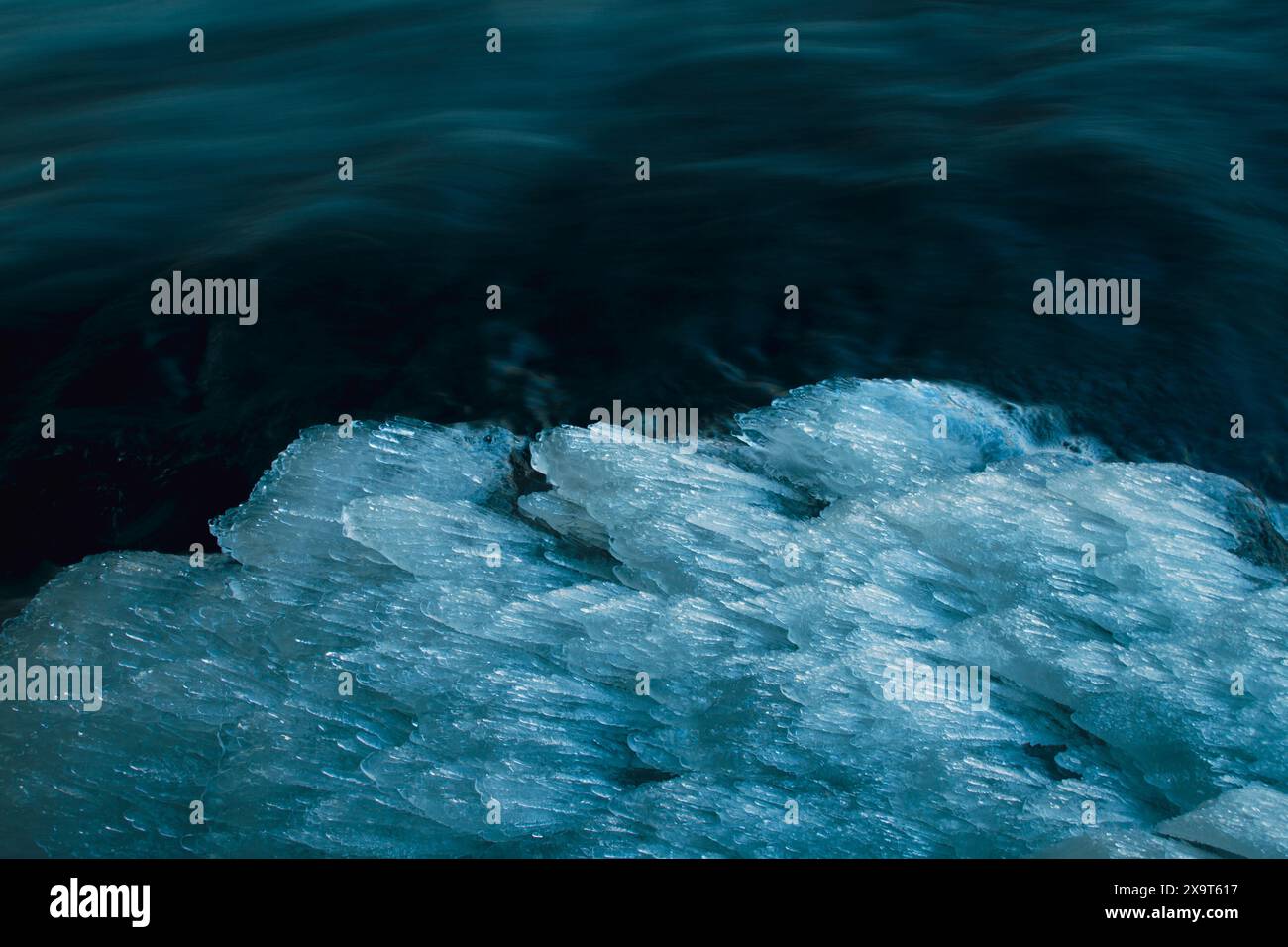 Foto ravvicinata di ghiaccioli che si formano sul lato di un flusso in rapido movimento. Foto Stock