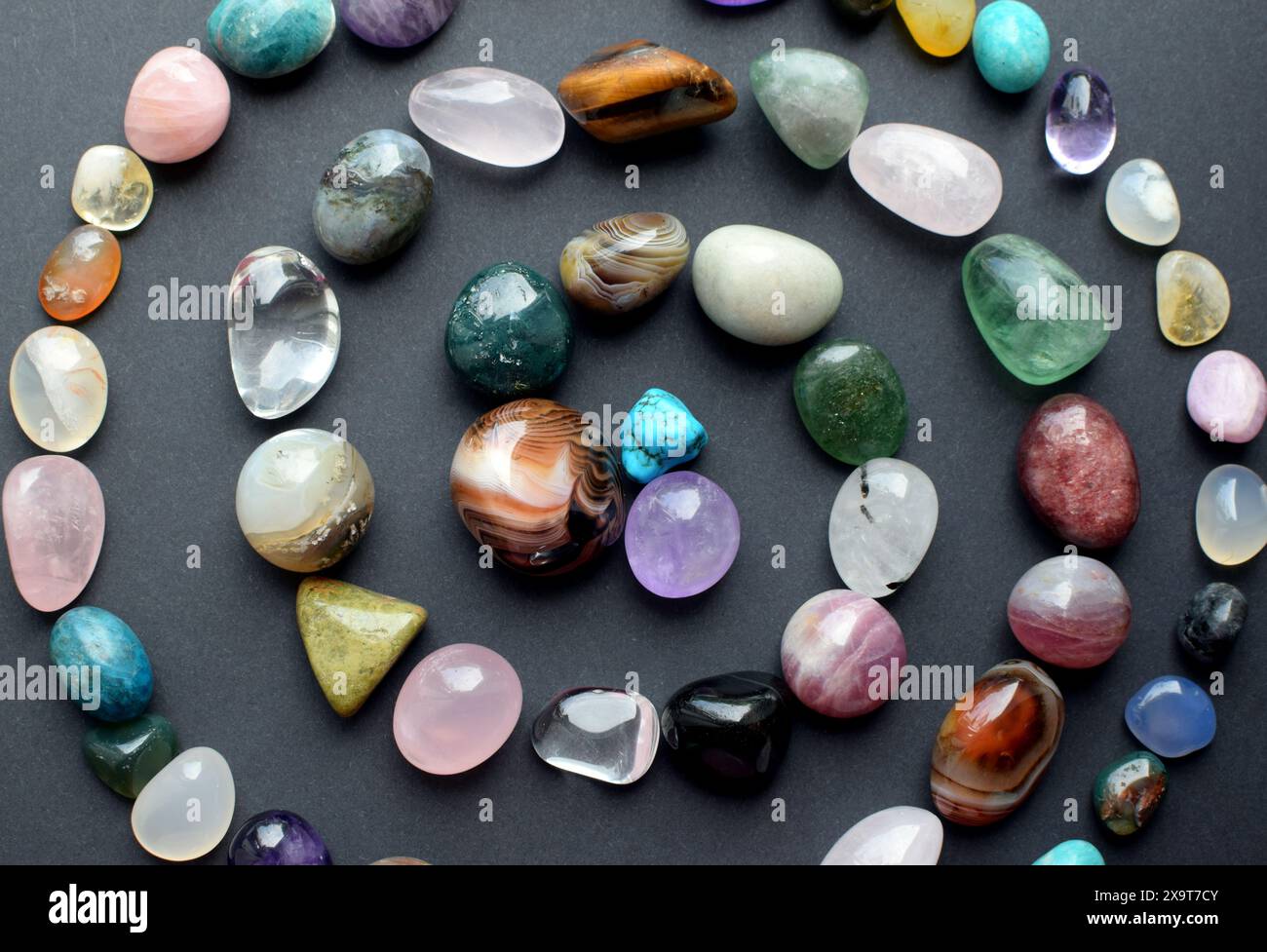 Le pietre naturali di diversi colori sono disposte sotto forma di spirale. Previsioni, stregoneria, pratica esoterica spirituale. Foto Stock