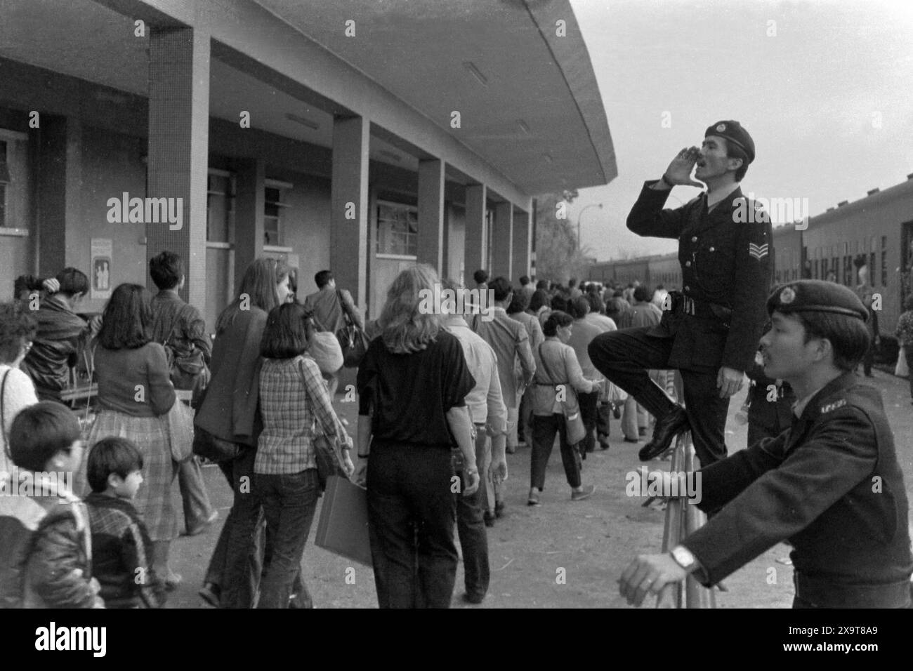 Passeggeri diretti a un treno diesel diretto a sud, alla stazione ferroviaria lo Wu, alla ferrovia Kowloon-Canton, Hong Kong, Capodanno lunare 1981. La folla in attesa è appena tornata a Hong Kong dalla Cina continentale. I poliziotti sulla piattaforma sono impegnati nella gestione della folla, a causa dell'elevato numero di passeggeri durante le festività. Foto Stock