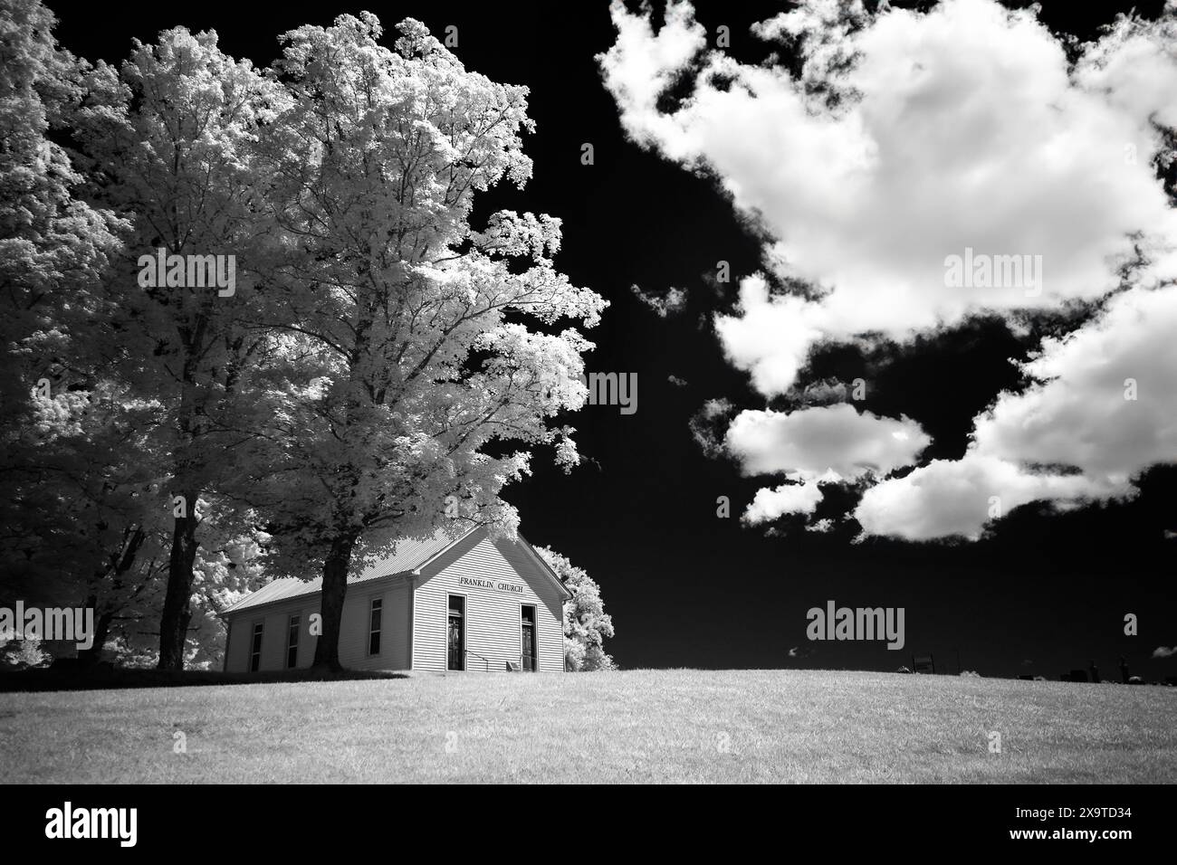 Un'immagine in bianco e nero ad alto contrasto di una piccola chiesa di campagna su una strada secondaria nel sud dell'Indiana. Le soffici nuvole contro un cielo nero fanno esplodere la scena Foto Stock