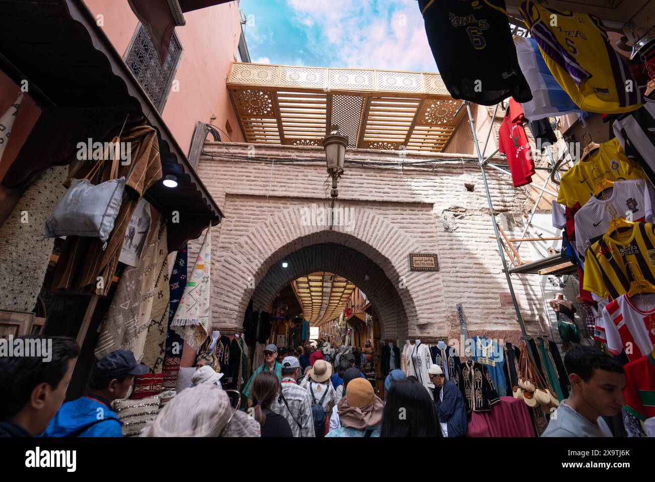 Jemaa el-Fnaa, Marrakech, Marocco - 18 marzo 2024: Sotto un cielo limpido, una folla energica si avvicina all'ingresso del mercato ad arco. Prodotti locali a disposizione Foto Stock