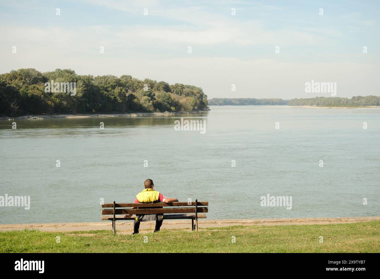 Uomo seduto in panchina sul Danubio ad Apatin, Vojvodina, Serbia Foto Stock