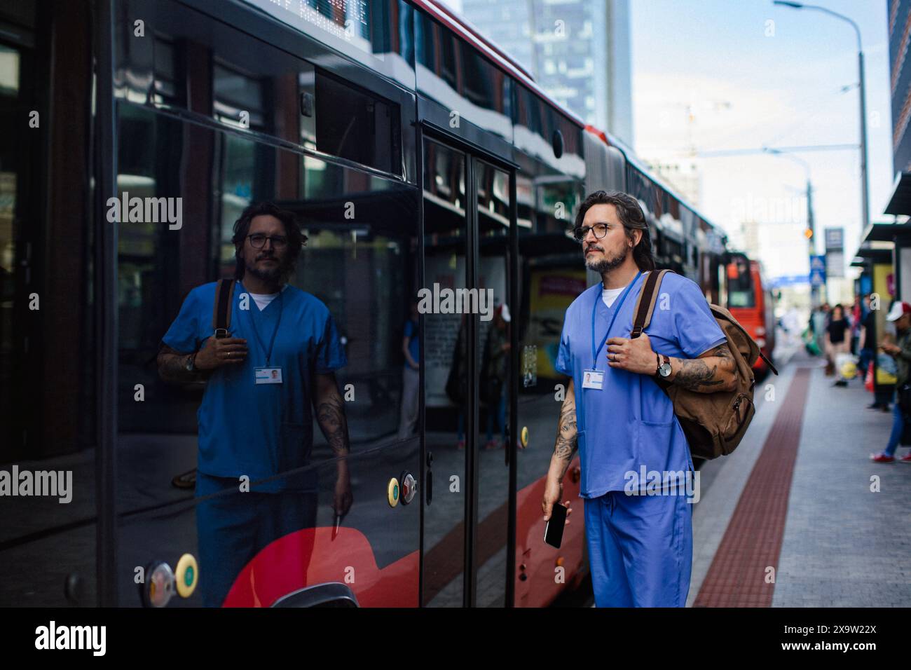 Dottore che ha portato foth alla fermata dell'autobus, tornando a casa dal lavoro. Equilibrio tra vita lavorativa e vita privata del lavoratore sanitario. Foto Stock