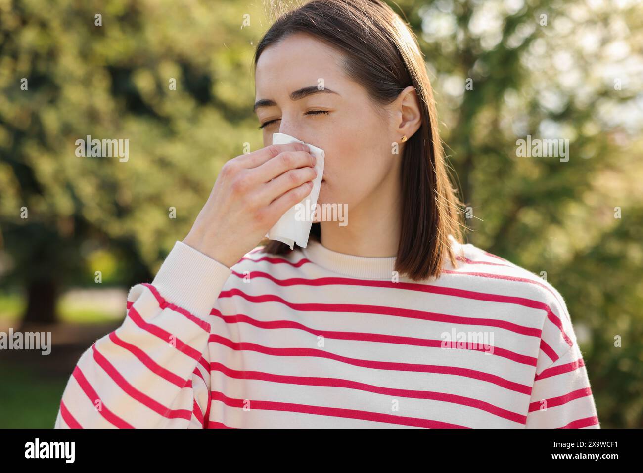 Donna con tovagliolo che soffre di allergia stagionale all'aperto Foto Stock