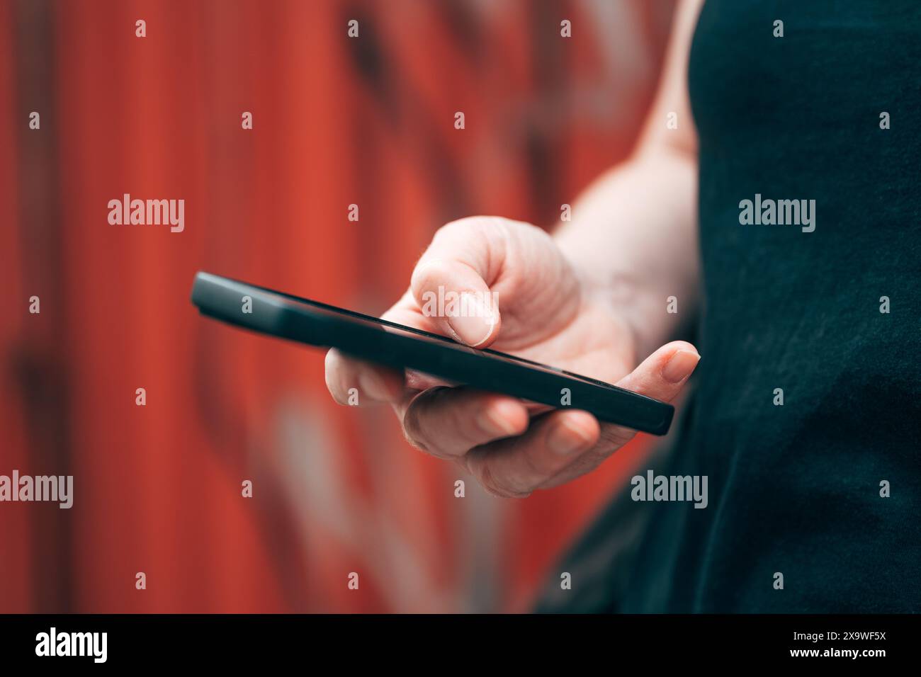 Comunicazione con il telefono cellulare. Donna che digita un messaggio di testo sullo smartphone mentre si trova all'aperto per strada. Messa a fuoco selettiva. Foto Stock