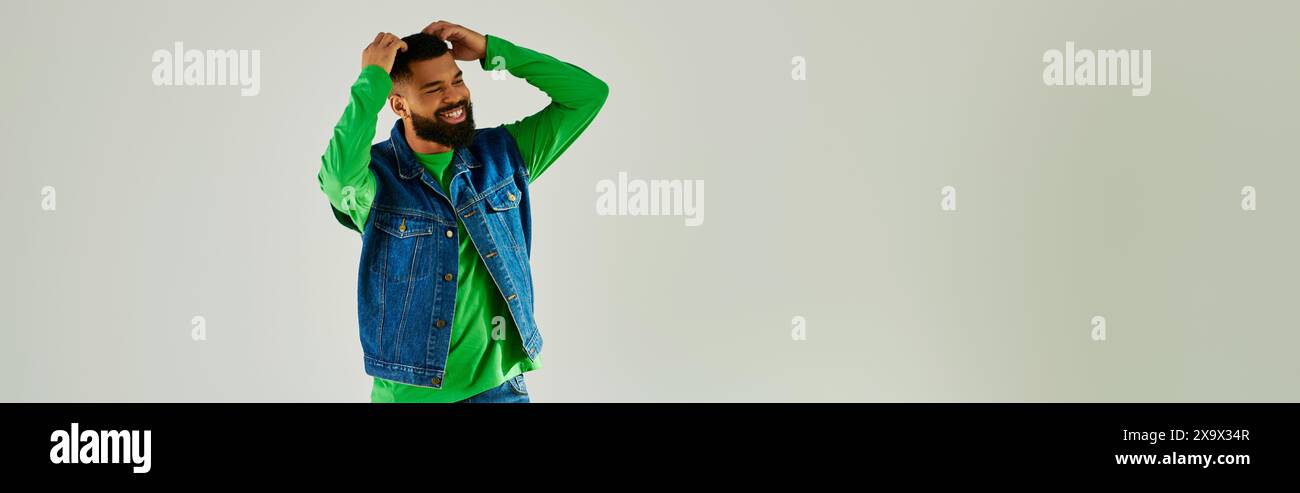 Un uomo con la barba che indossa una manica lunga verde e jeans blu. Foto Stock
