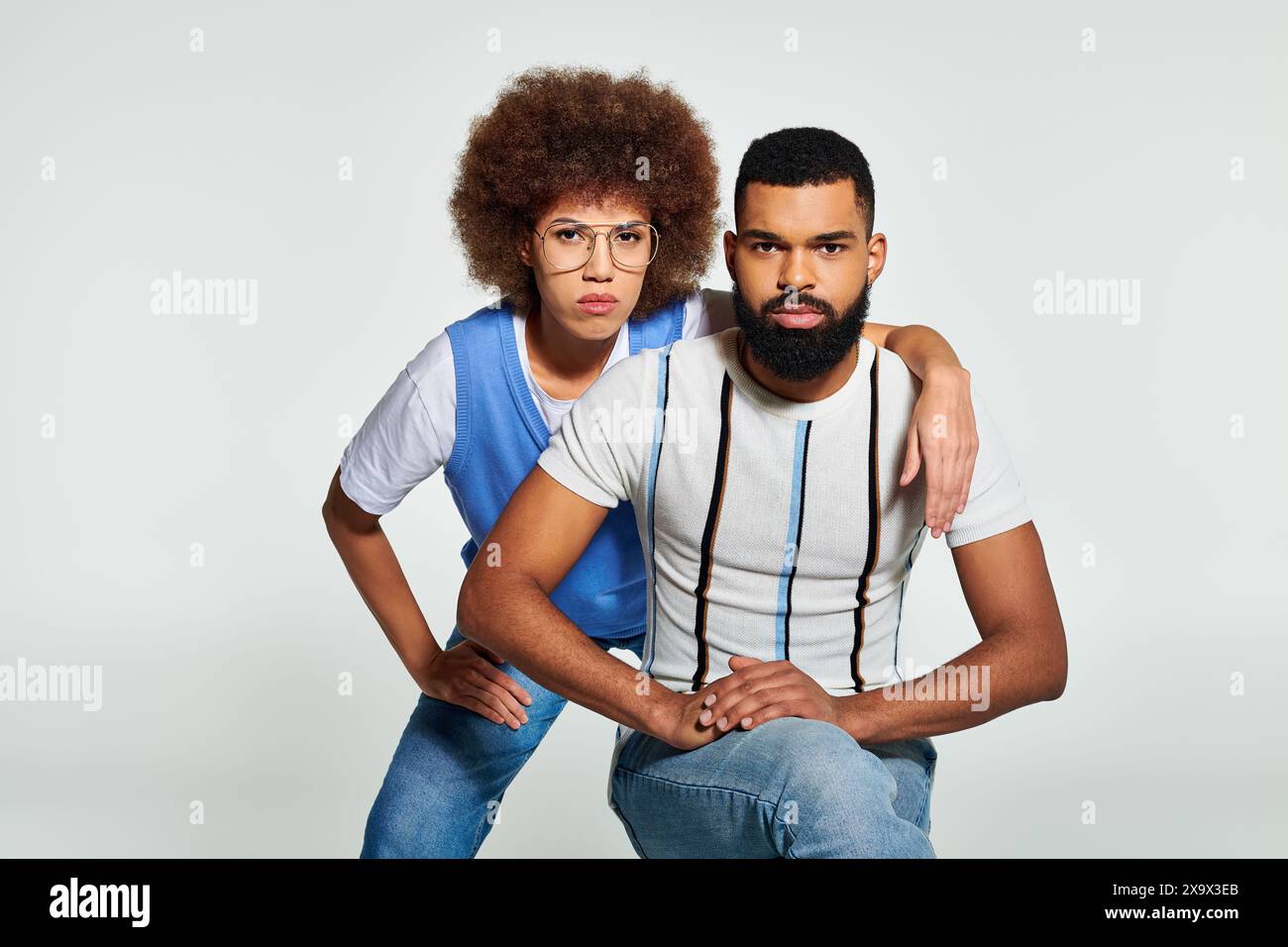 Un uomo e una donna afroamericani vestiti con abiti eleganti posano per una foto su uno sfondo grigio. Foto Stock