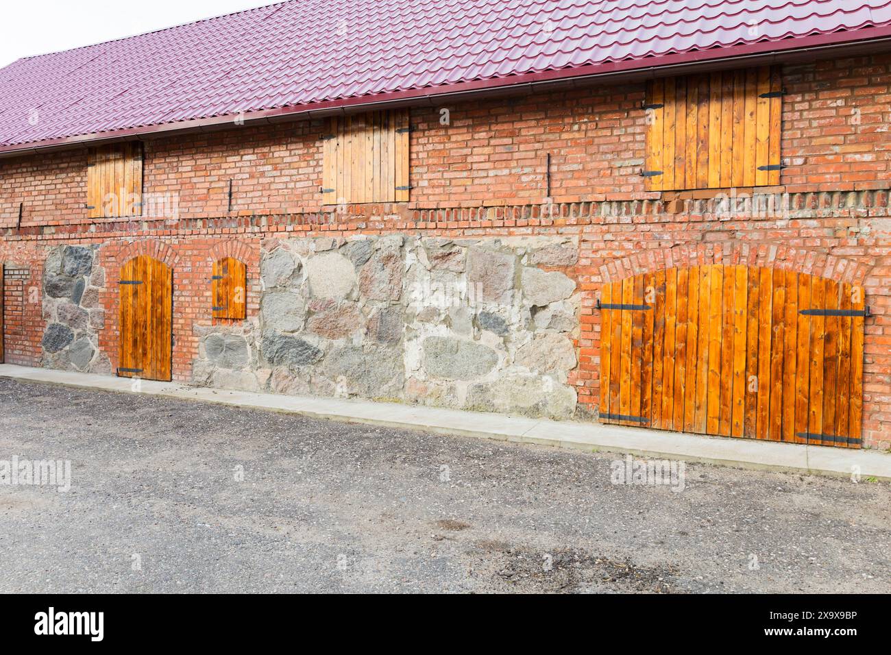 Una parete in mattoni e' completata da persiane di legno sulle finestre dell'edificio Foto Stock