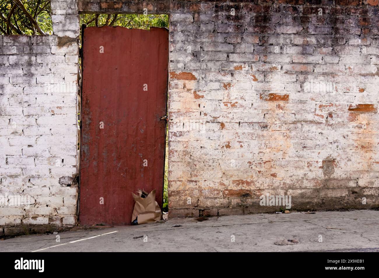 La facciata in mattoni bianchi, con un sacchetto di carta alla porta metallica, di una casa originale nella città di Arcabuco, nelle Ande orientali Foto Stock