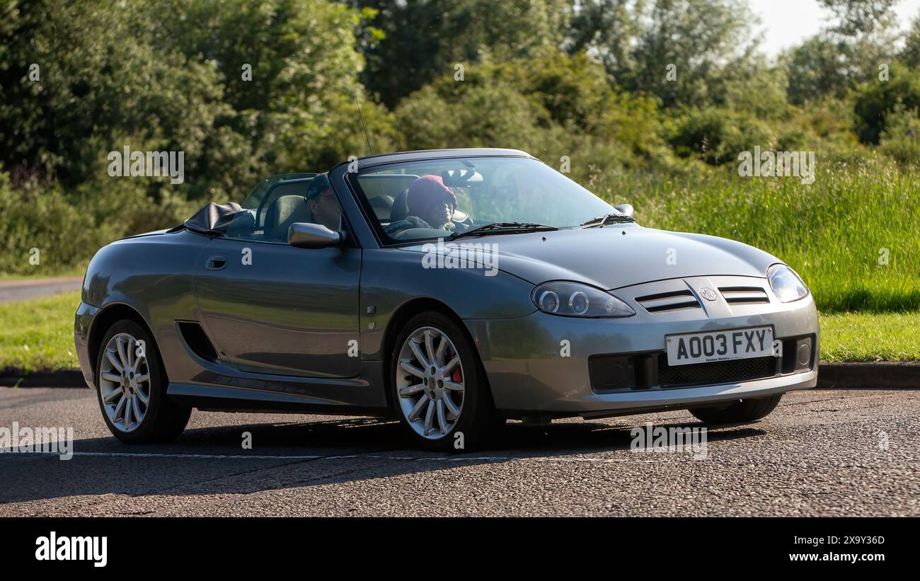Stony Stratford, Regno Unito - 2 giugno 2024: 2003 auto MG TF grigia che guida su una strada di campagna britannica Foto Stock
