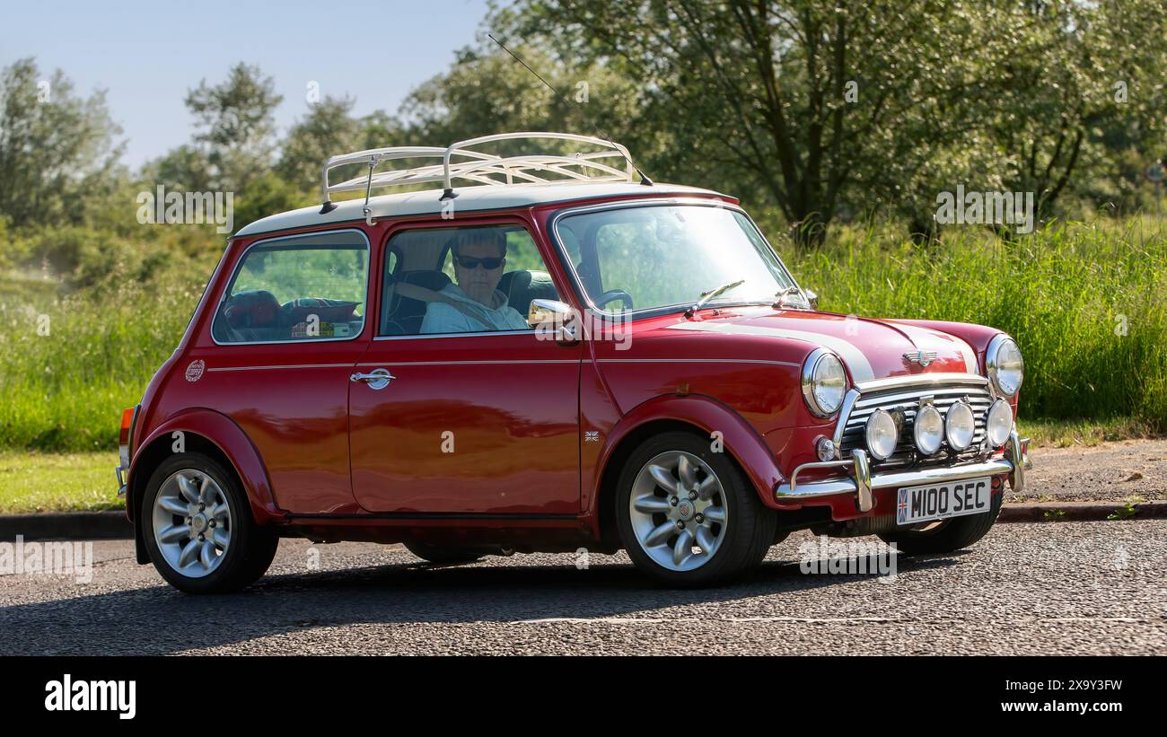 Stony Stratford, Regno Unito - 2 giugno 2024: 2000 Rover Mini Cooper rossa che guida su una strada di campagna britannica Foto Stock