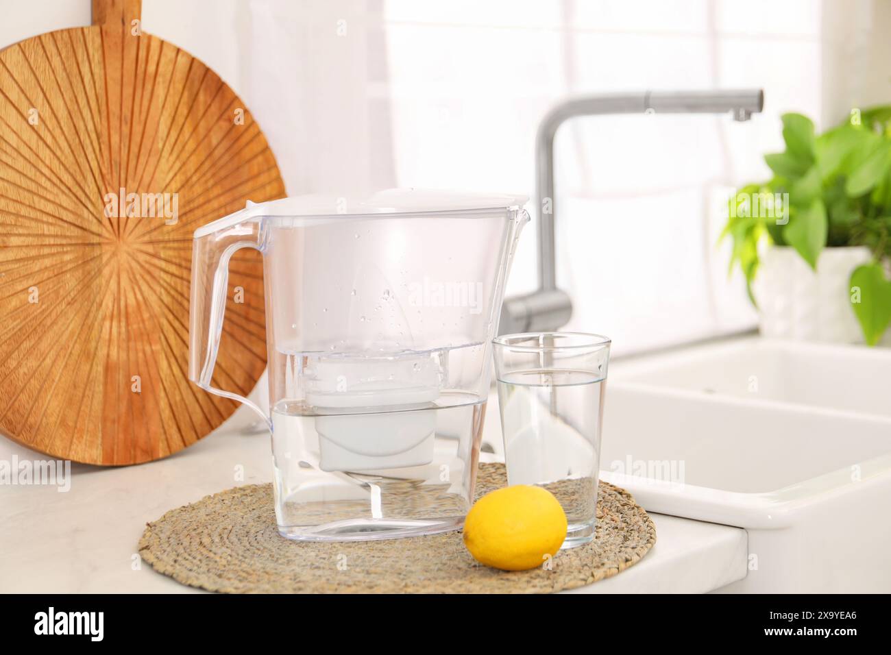 Caraffa del filtro dell'acqua, bicchiere e limone sul ripiano in cucina Foto Stock