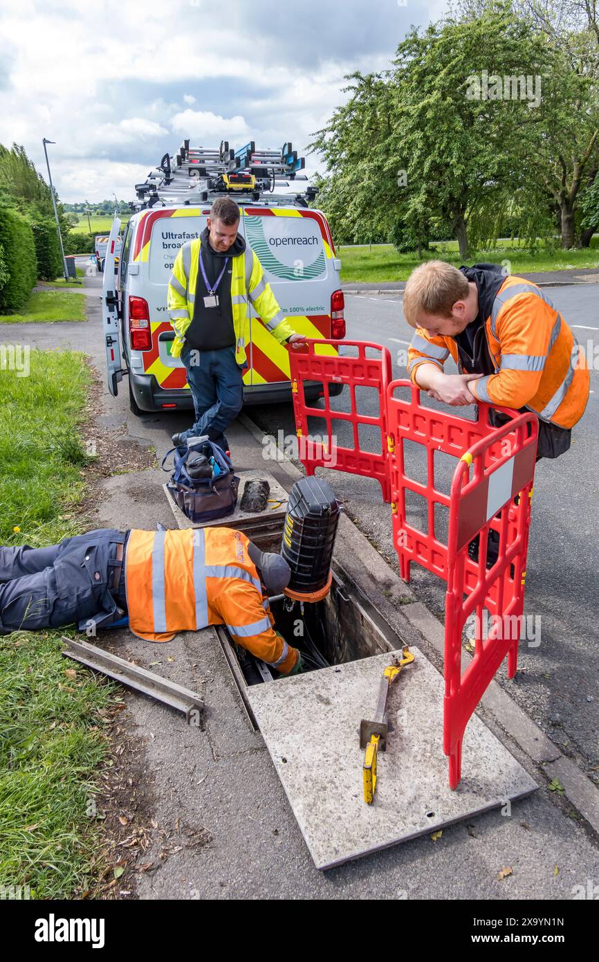 Ingegnere Openreach che lavora sul cablaggio in tombino, Church Lane, Cherry Willingham, Lincoln, Lincolnshire, Inghilterra, Regno Unito. ARW Foto Stock