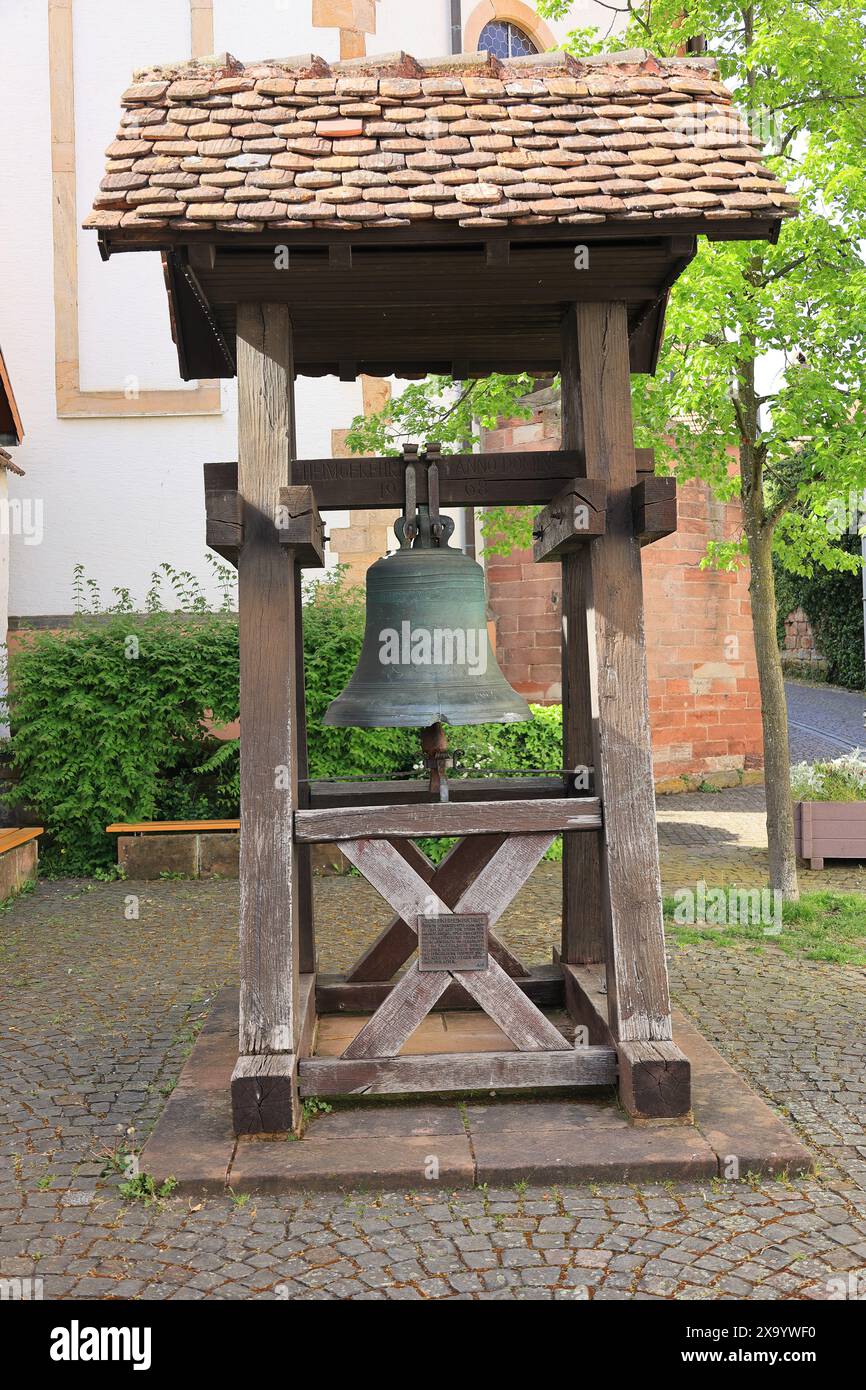 Campana di fronte alla chiesa di montagna di Bad Bergzabern in una cornice di legno Foto Stock