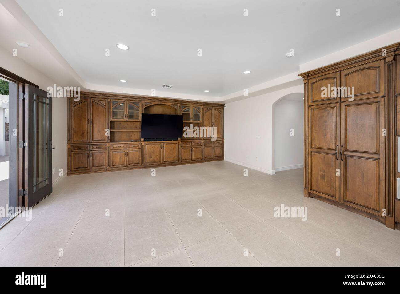 Un interno minimalista del soggiorno con uno spazioso armadio e televisore a Encino, California Foto Stock