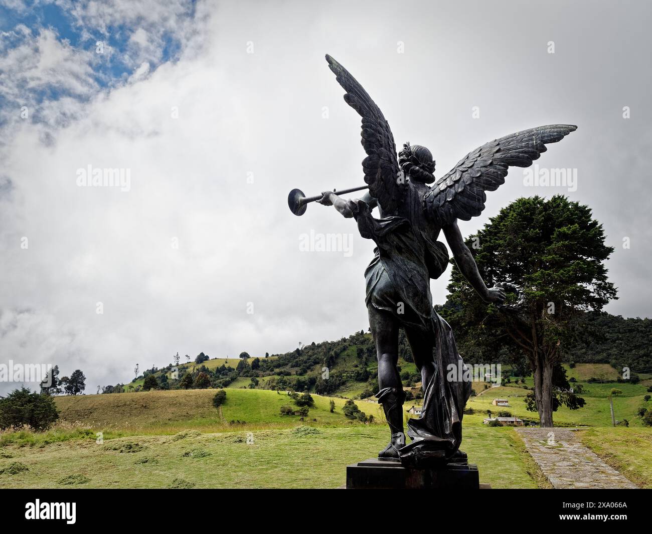 Una monumentale scultura di angelo con una tromba su uno sfondo verde lussureggiante Foto Stock