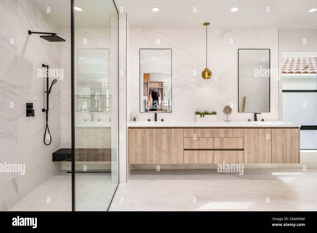 Un bagno con due lavandini, ripiani in marmo e box doccia in vetro Foto Stock