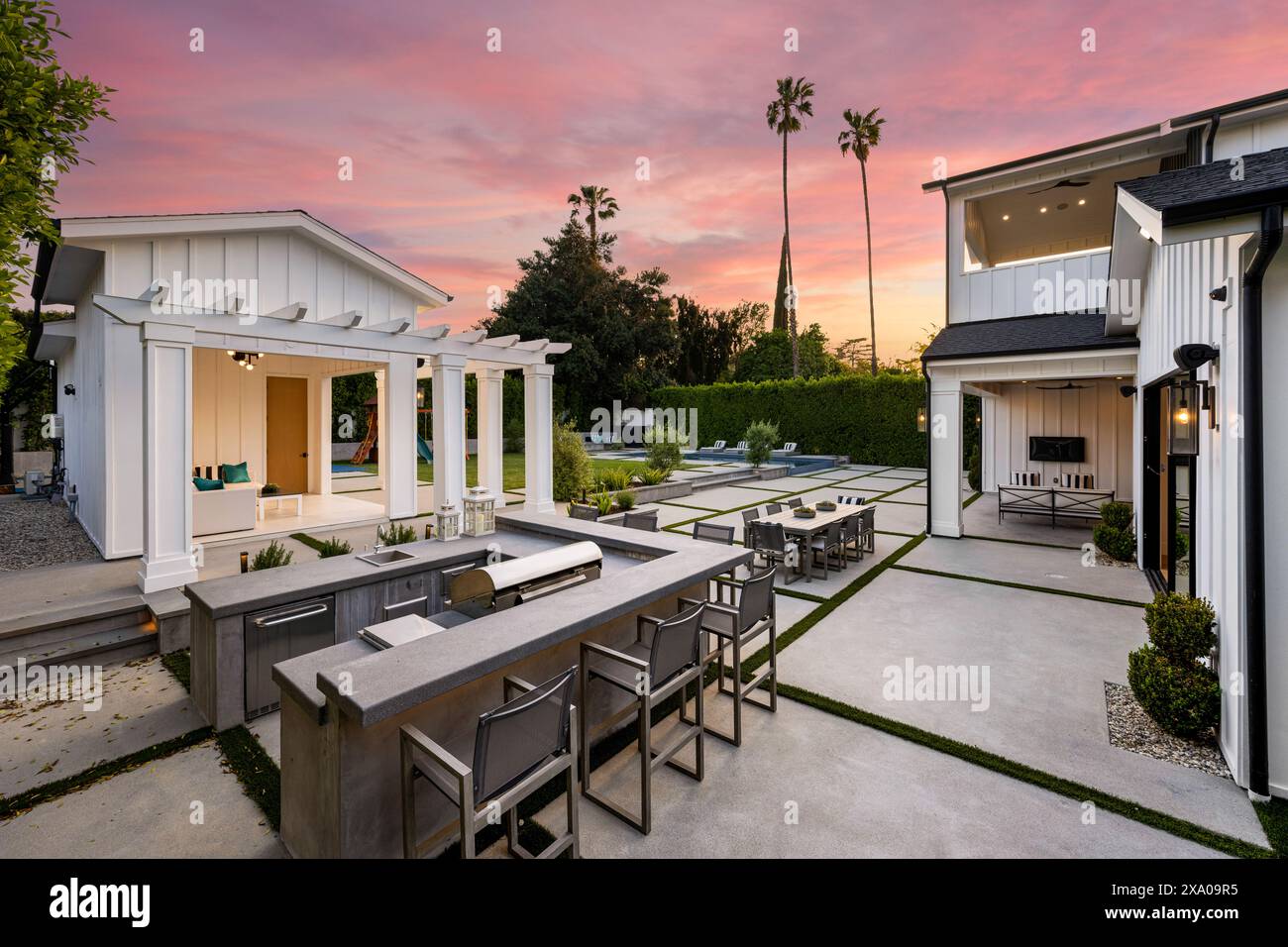 Una cucina all'aperto con caminetto, tavolo e sedie illuminati dalla luce della sera Foto Stock