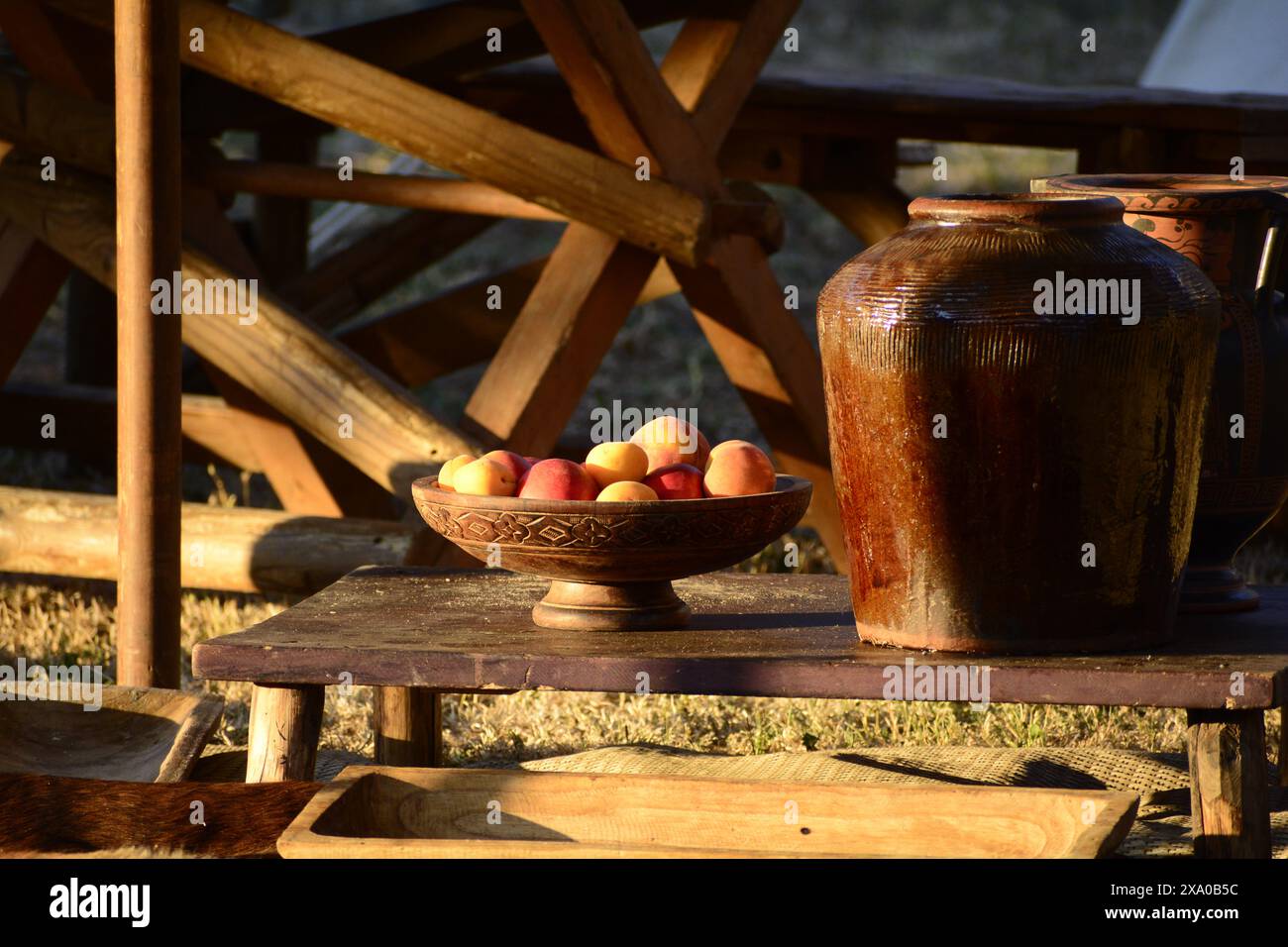 Una ciotola di frutta e una ghiaia di argilla su un tavolo di legno alla luce del sole dorato Foto Stock