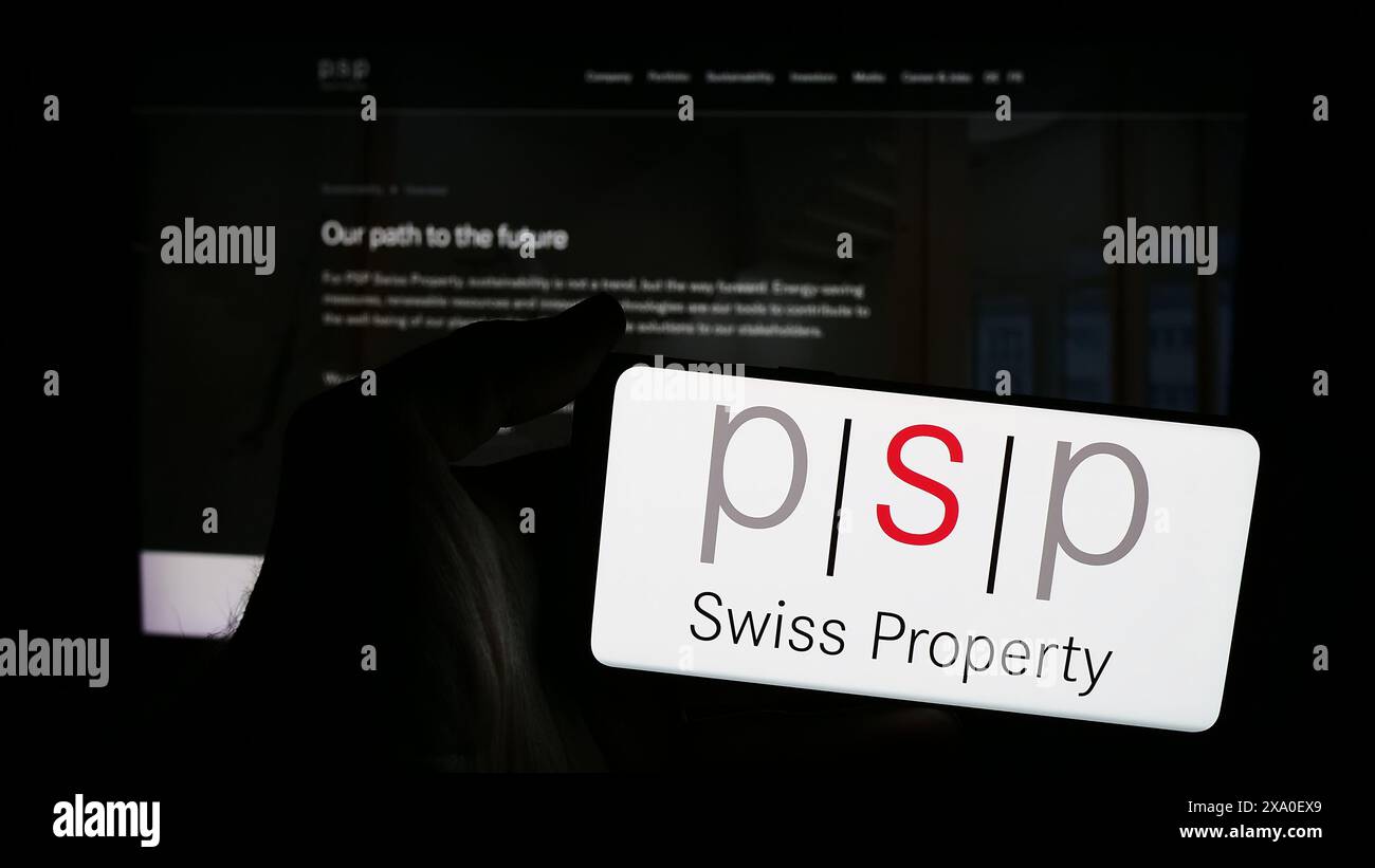 Persona che detiene lo smartphone con il logo della società immobiliare PSP Swiss Property AG davanti al sito web. Mettere a fuoco il display del telefono. Foto Stock