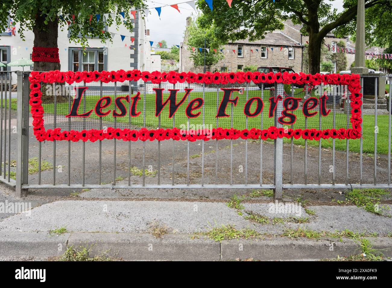 "Lever We Forget" con papaveri lavorati a maglia da donne locali di Long Preston. In mostra al villaggio 3/6/24 con altri grandi gruppi di papaveri lavorati a maglia . Foto Stock