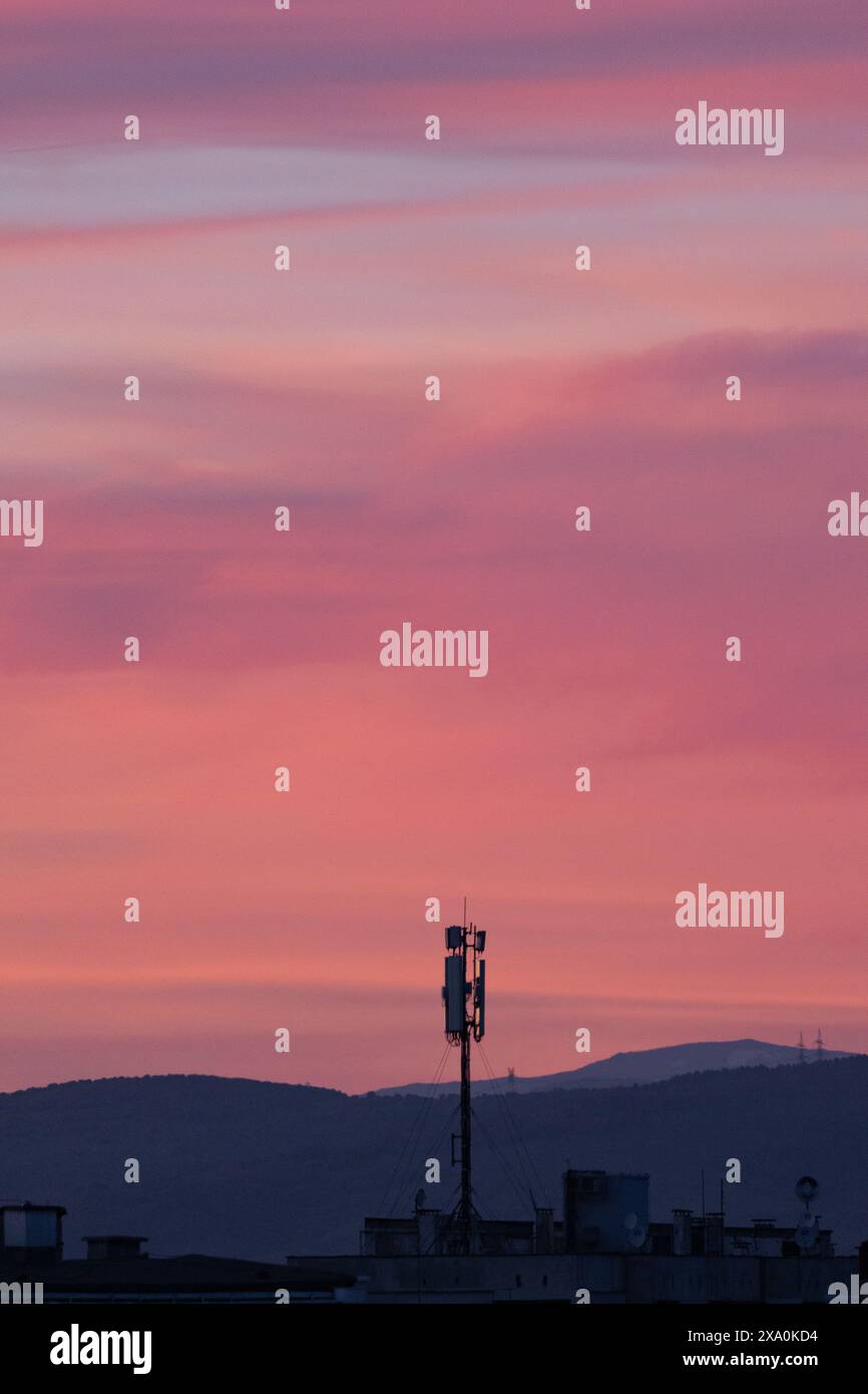 Un tramonto sullo skyline della città e sulle colline sullo sfondo. Foto Stock