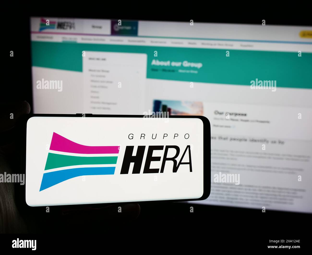 Persona che possiede uno smartphone con il logo della società italiana Hera S.p.A. davanti al sito web. Mettere a fuoco il display del telefono. Foto Stock