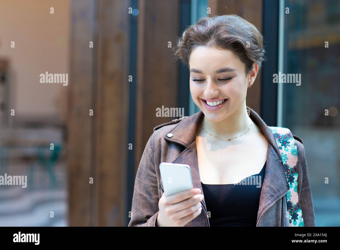 Bella donna sorridente che legge un messaggio di testo sul suo cellulare Foto Stock