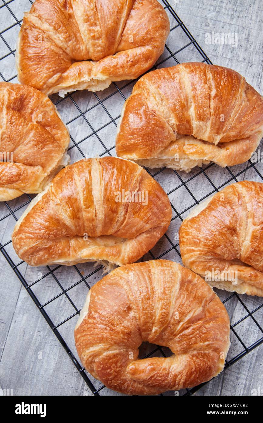 I croissant appena sfornati si raffreddano su una griglia metallica Foto Stock