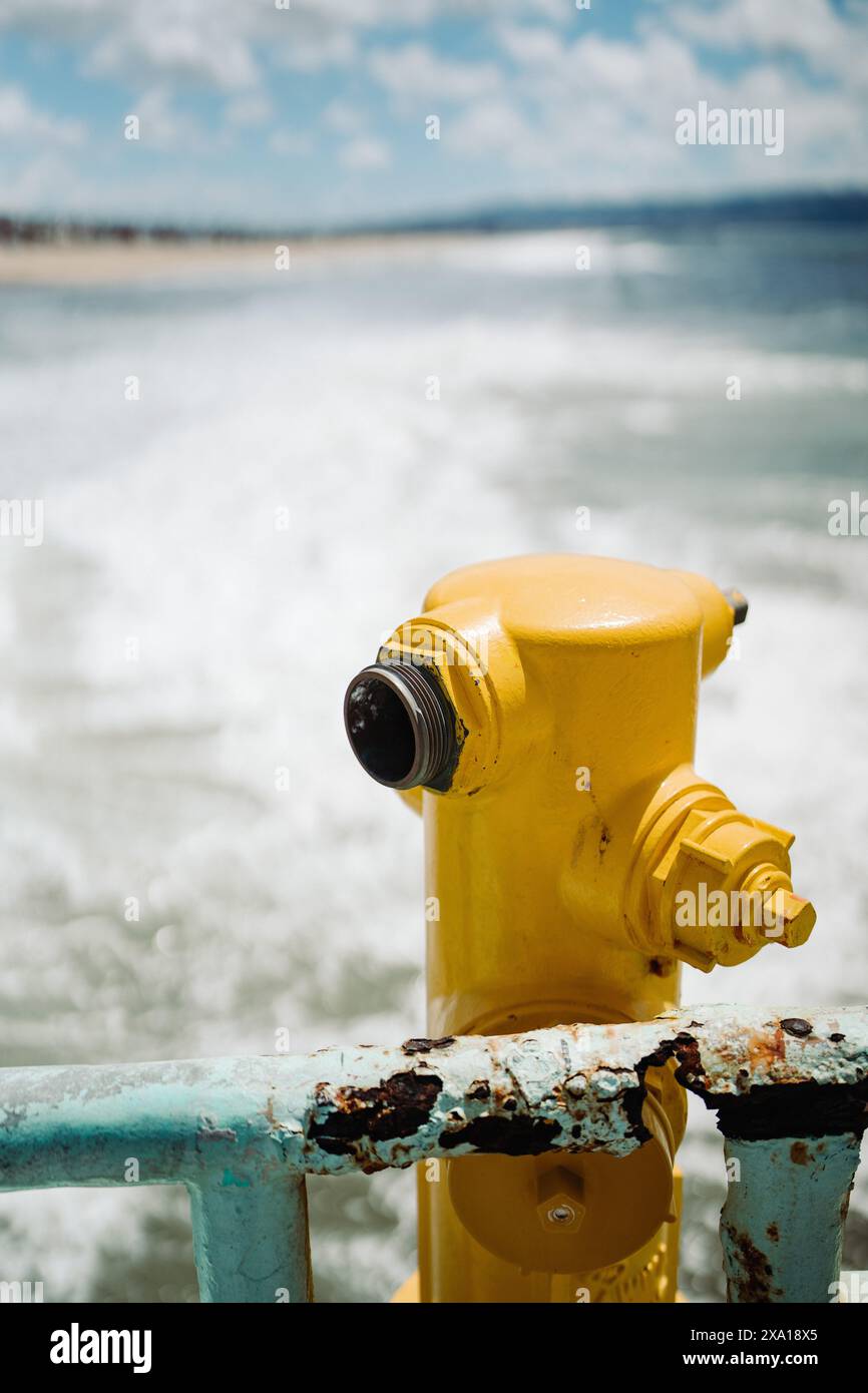 Un idrante giallo contro uno sfondo d'acqua Foto Stock Un idrante giallo contro uno sfondo d'acqua Foto Stock